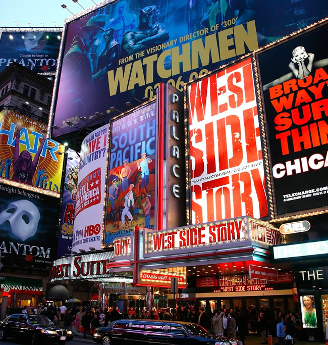 A vibrant display of illuminated billboards and theater signs in Times Square, showcasing various musical productions including 'West Side Story' and 'South Pacific'.