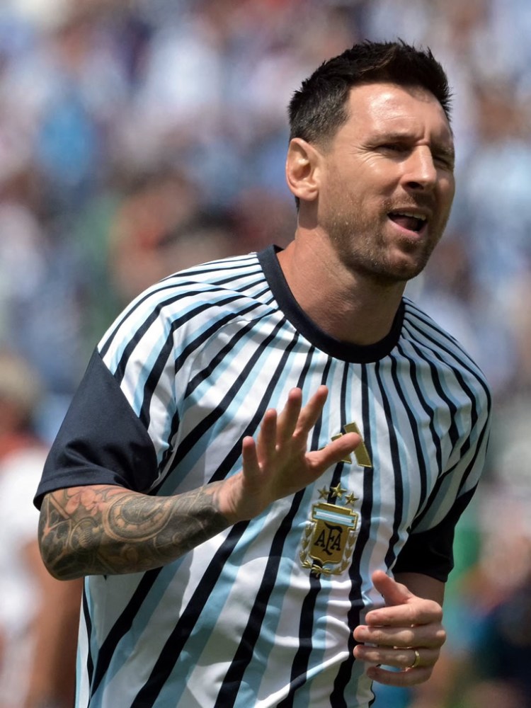 A soccer player wearing a striped jersey with the Argentina national team logo, gesturing during a match.
