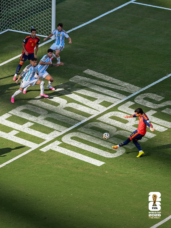 A soccer player in a red jersey prepares to kick the ball from near the goal, surrounded by opposing players in blue and white jerseys, with large text reading 'Fernando Torres' on the field.