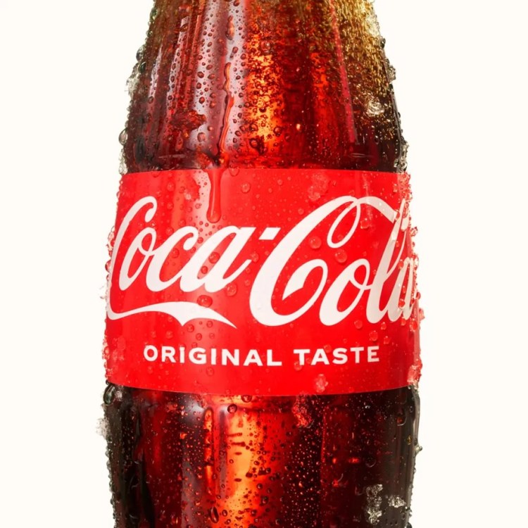 Close-up of a Coca-Cola bottle with condensation, featuring the label that reads 'Coca-Cola Original Taste'.