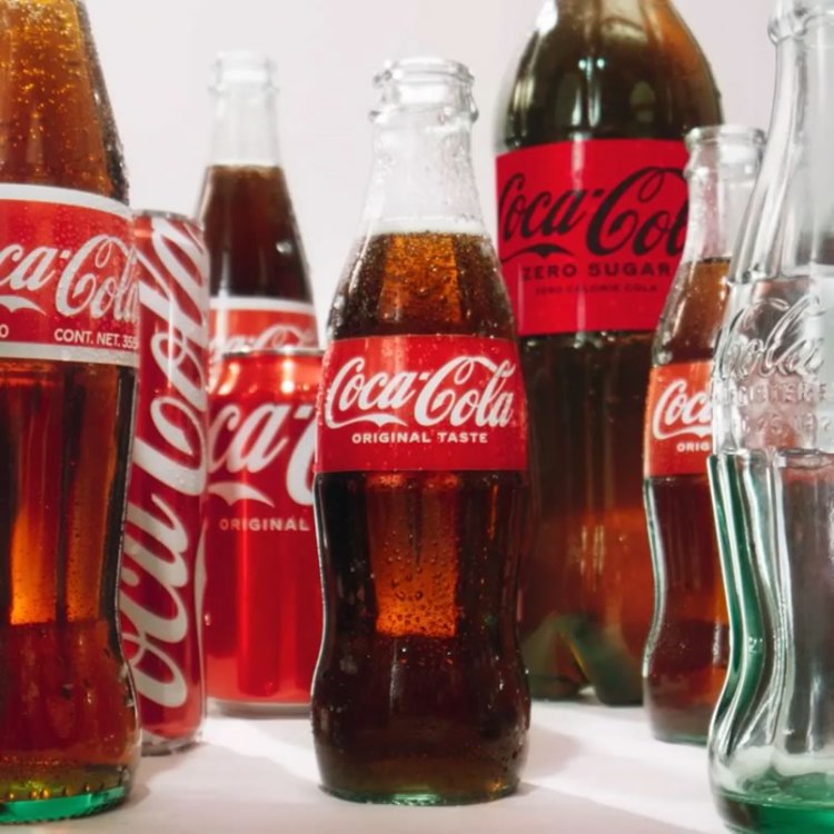 Various Coca-Cola bottles featuring original taste and zero sugar options, placed on a surface with visible condensation.